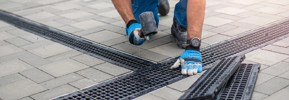 Person verlegt mit Gummihammer eine Regenrinne.